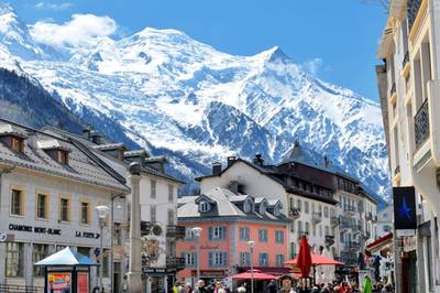 Buildings in central Chamonix with mountains behind them, under a cloudy sky.